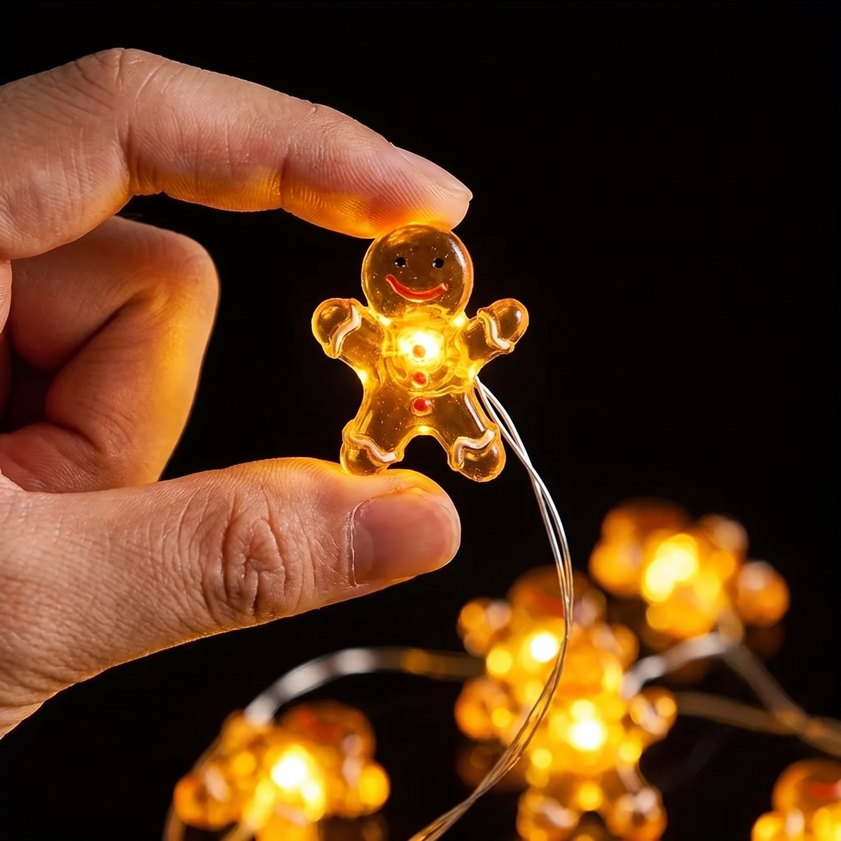 Närbild på en av Dulces pepparkaksgubbar: ansikte, knappar och det varma skenet inifrån – liten nog att hålla mellan två fingrar