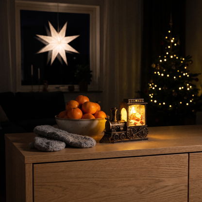 Julius tänd på en ekbyrå bredvid klementiner och vantar, adventsstjärnan och granen lyser i det mörka rummet
