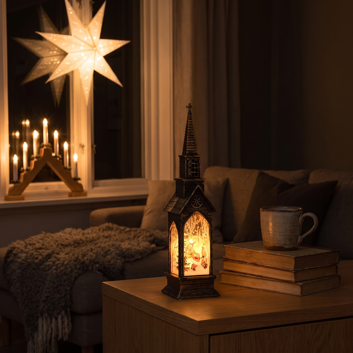 Ett mörkt vardagsrum första advent: adventsstjärnan i fönstret, ljusstaken på brädan och Vesper som lyser på skänken bredvid en kopp och några böcker